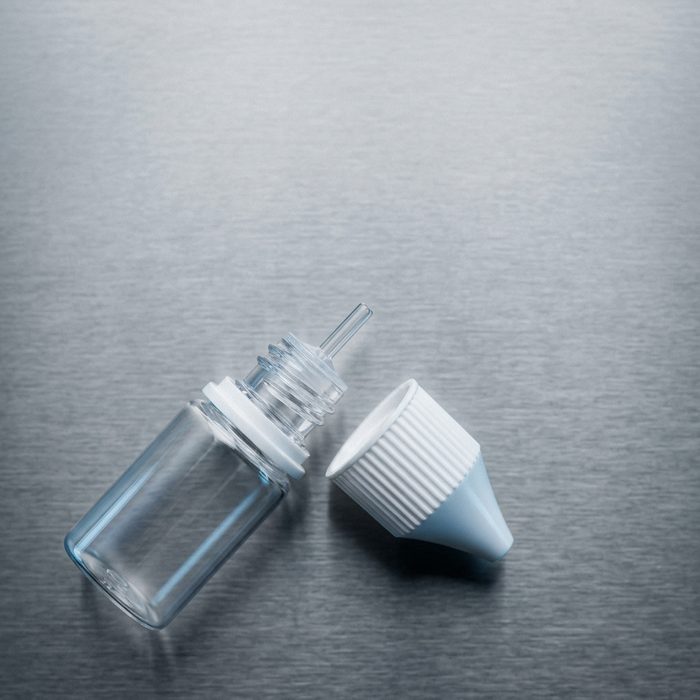 An opened 10 ml bottle with the child-resistant cap beside it and the dropper spout still in the neck.
