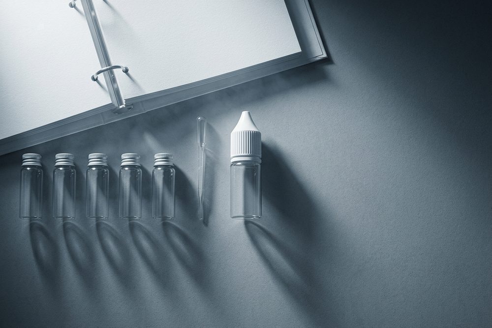 A row of sample vials, a pipette and an open binder on a dark worktop.